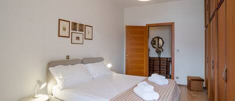 A neatly arranged bedroom with a bed, bedside lamp, and a small table.