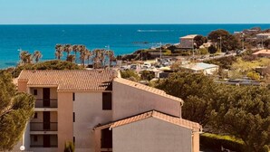 Une zone résidentielle côtière avec des bâtiments, un ciel bleu dégagé et la mer en arrière-plan.