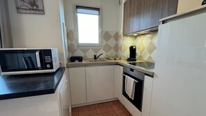 A compact kitchen with white cabinets, a built-in microwave, a coffee maker, and a window.