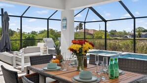 Patio luminoso con tavolo da pranzo, sedie, una piccola piscina e vista sul paesaggio circostante.