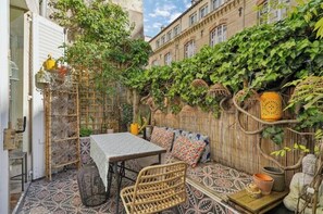 Eine Terrasse im Freien mit Tisch und Stühlen, einem gemusterten Teppich und einem Bambuszaun.