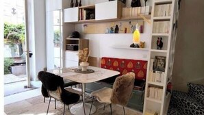 Un salon moderne avec une table à manger, deux chaises, une bibliothèque et un mur décoré d’un motif rouge.