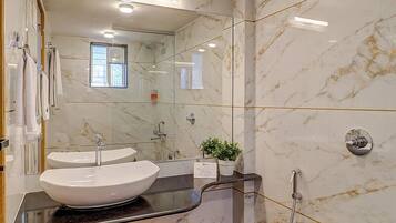 Een moderne badkamer met een grote spiegel, een witte wastafel, een douche en een toilet.