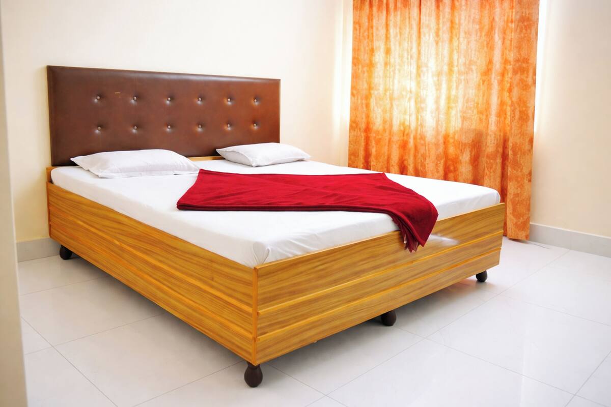 A bed with a wooden frame, white bedding, and a red throw blanket.