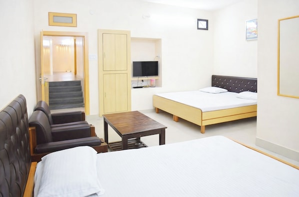 A hotel room with a bed, a sofa, a TV, a wardrobe, and a small table.