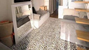 Een modern interieur met een hoge plafond, een grote geweven lamp, een vloer met luipaardprint en een trap met houten treden.