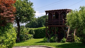 A wooden tower structure with a staircase, surrounded by lush greenery and a cobblestone path. - Holiday Home 'Jasmim' with Mountain View, Wi-Fi and Air Conditioning (Guimarães)
