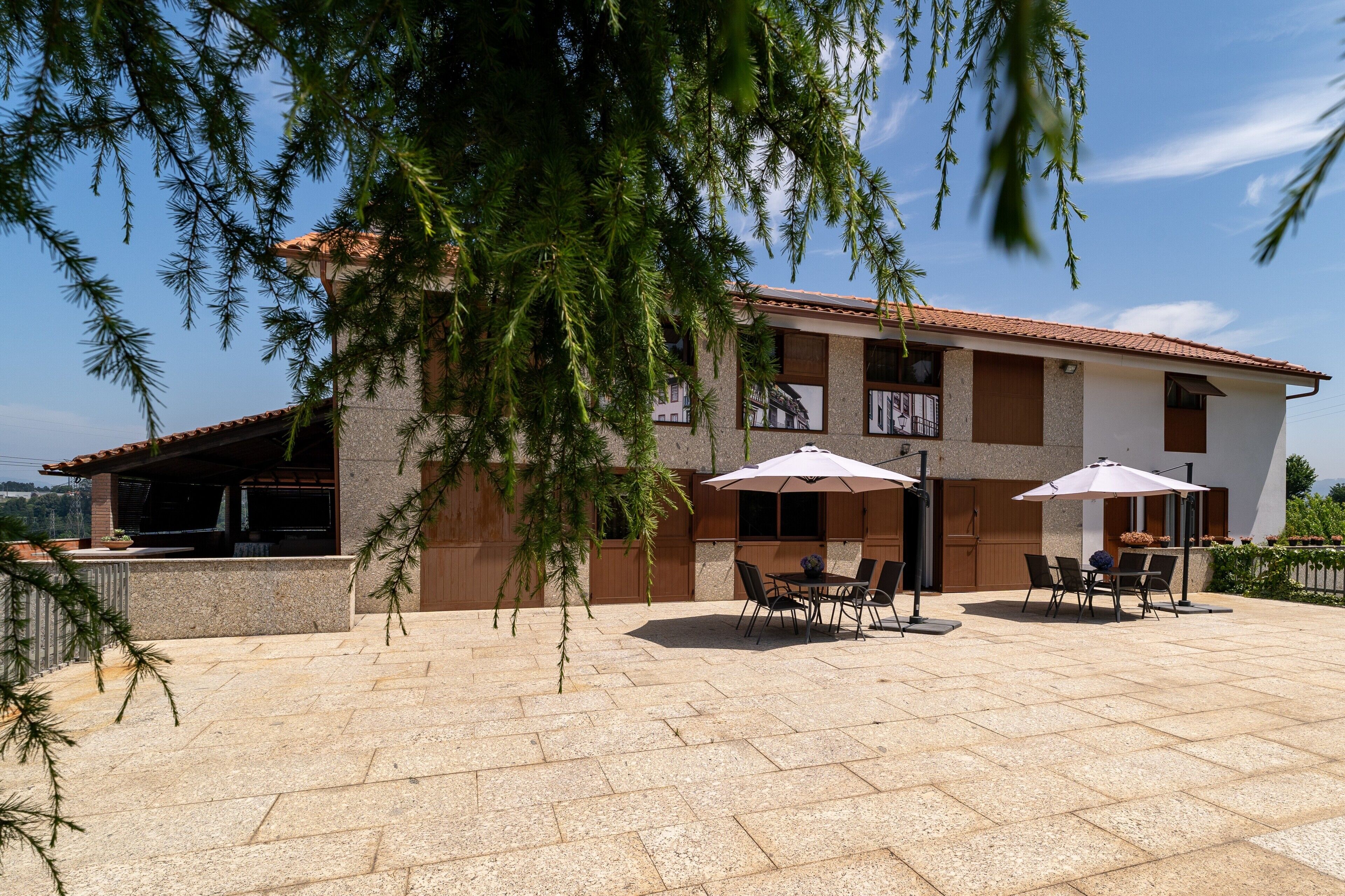 A two-story building with a patio area featuring outdoor seating and umbrellas.