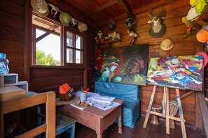 Une pièce rustique avec des murs en bois, un bureau en bois, une fenêtre et deux tableaux accrochés au mur.
