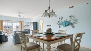 A dining area with a wooden table, white chairs, a chandelier, and a decorative wall piece. - Charming retreat on 14th Street overlooking the canal White Marlin Open takes place, close to the beach and boardwalk (Ocean City)