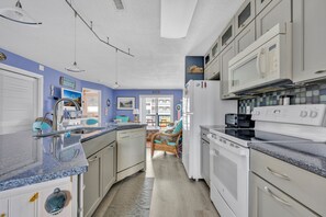 A kitchen with white appliances, a granite countertop, and a view to the dining area. - Two bedroom mid-town condo with a pool! (Ocean City)