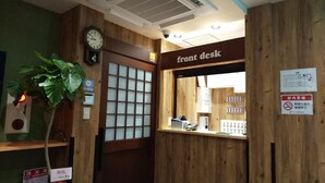 Ein Empfangsbereich mit einem Holztisch, einer Uhr und einem Schild mit der Aufschrift 'front desk'.