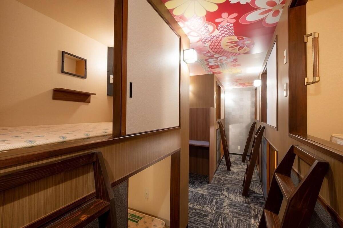 Pasillo de hotel con bancos de madera, un espejo y un techo con motivos florales.