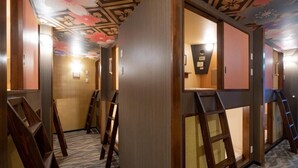 Ein Hotelzimmer mit Holzboden, Decke mit floralem Muster und einer Schiebetür.