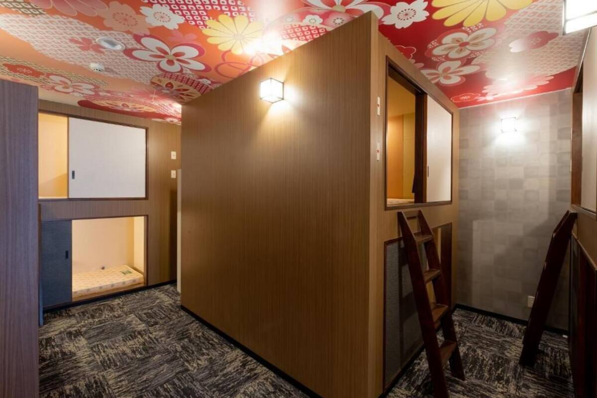 Una habitación con un separador de madera, una escalera y una alfombra estampada.