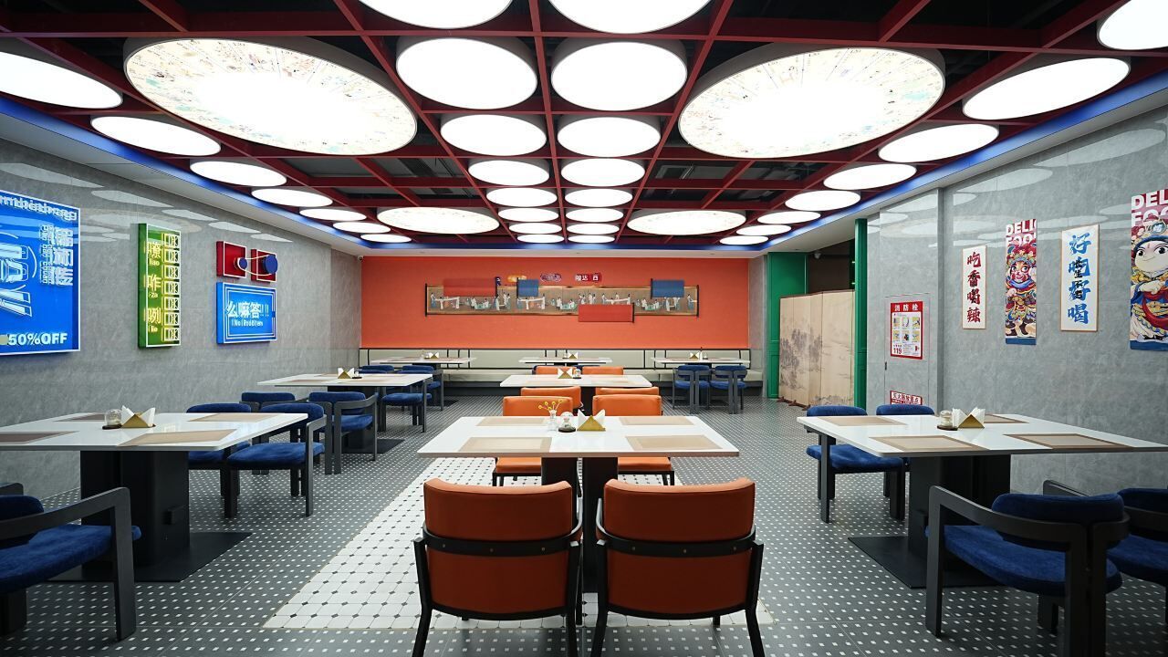 A conference room with tables and chairs, a patterned floor, and a red accent wall with artwork.