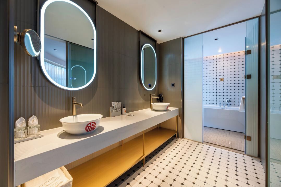 A modern bathroom with two sinks, large mirrors, and a glass shower enclosure.