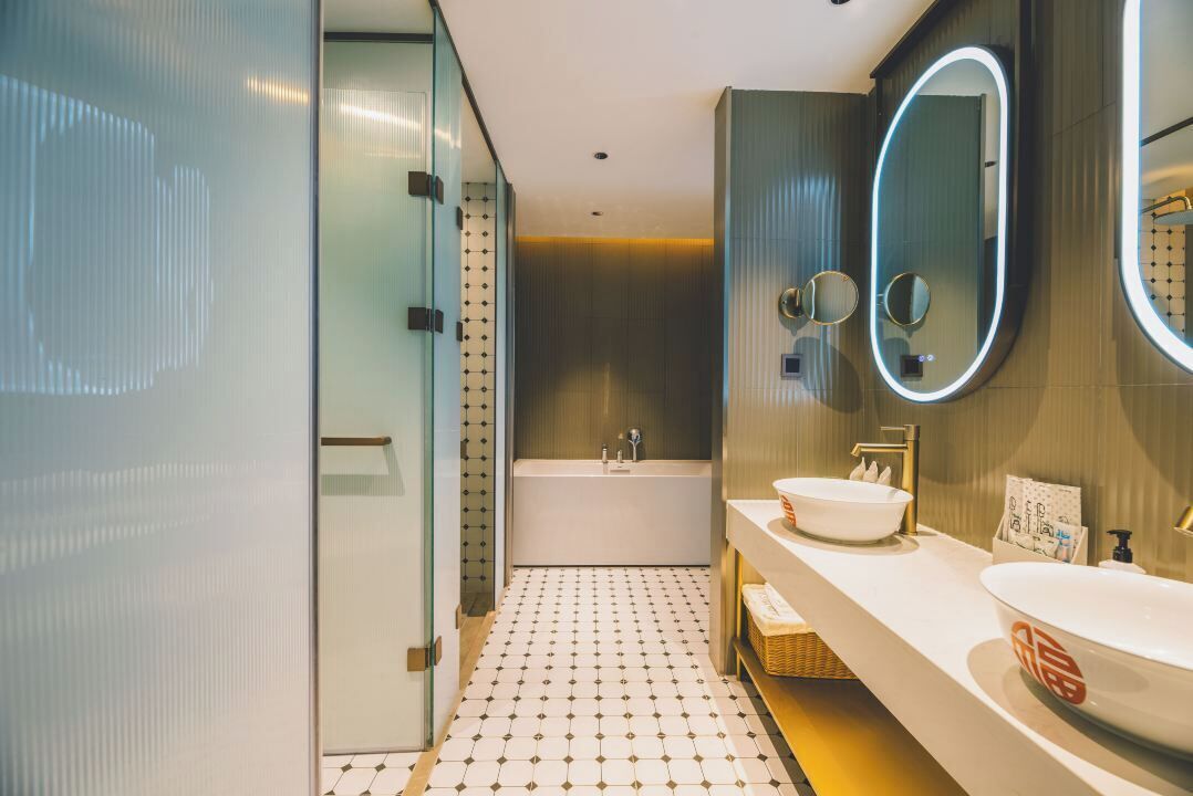 A modern bathroom with a bathtub, two sinks, and a large mirror.
