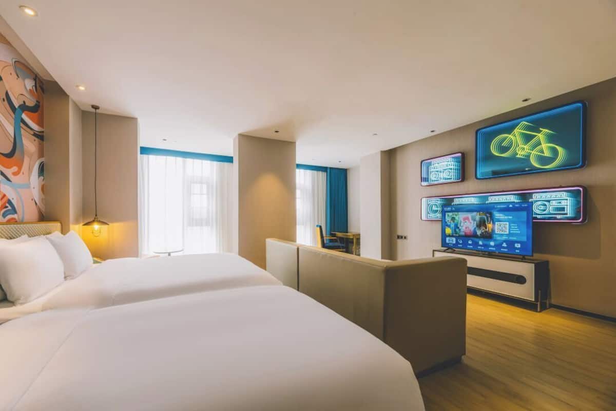 A hotel room with a large bed, a seating area, a TV, and neon bicycle signs.