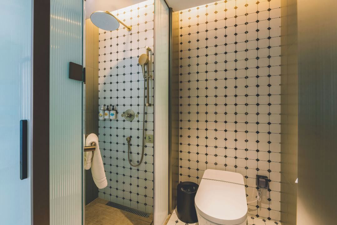 A bathroom with a shower, toilet, and a towel rack.