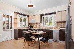 A modern kitchen with a dining table, chairs, a dishwasher, and a TV.