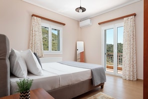 A bedroom with a bed, a bedside table with a plant, a window, and a balcony.