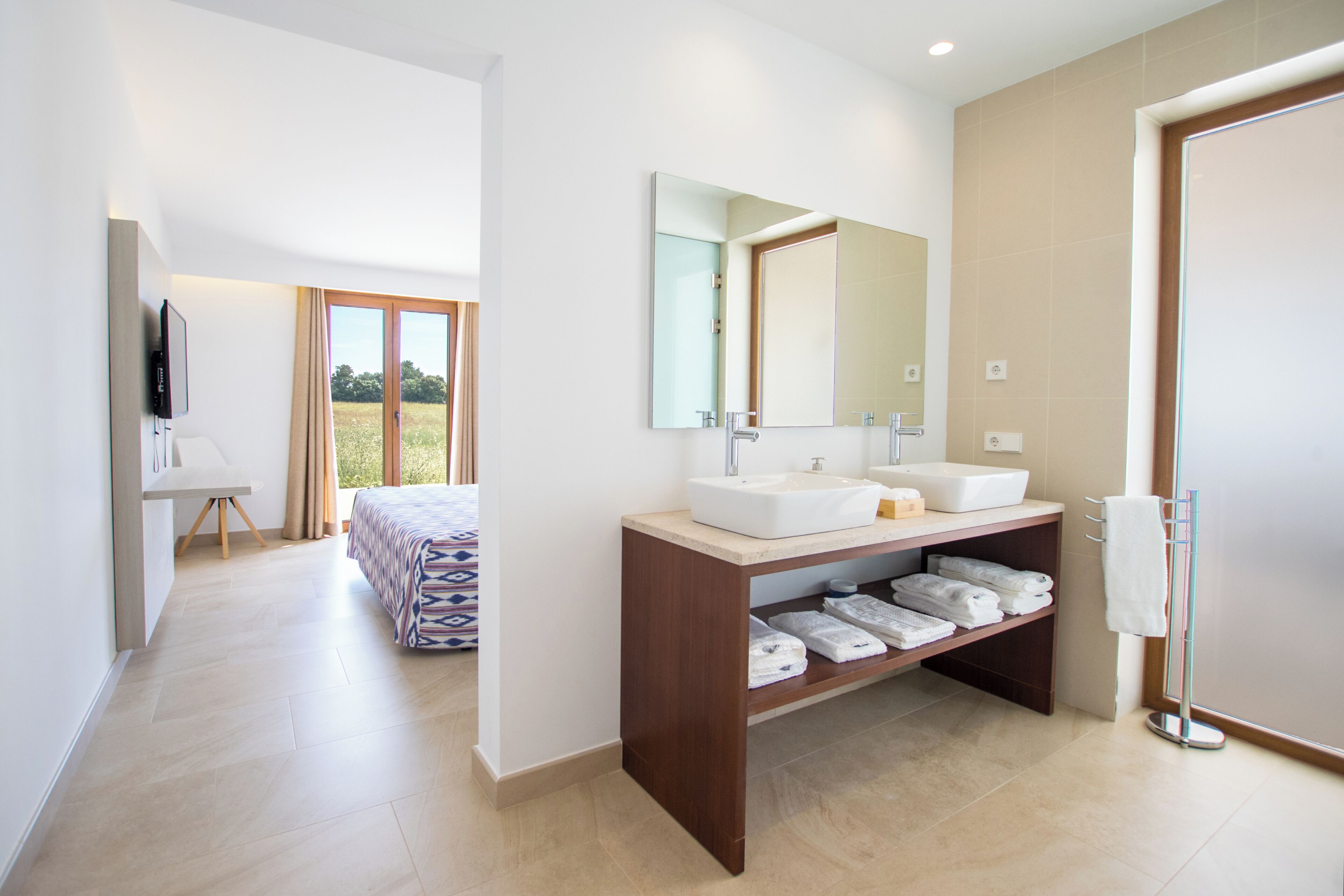 Un baño moderno con dos lavamanos, un espejo grande y un perchero para toallas.