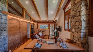 Un interior acogedor con una mesa de madera dispuesta para dos, paredes de piedra y una chimenea de piedra.