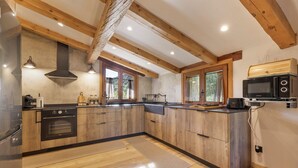 Una cocina moderna con vigas de madera, electrodomésticos integrados y ventanas amplias.