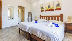 Une chambre d’hôtel avec deux lits, une tête de lit en bois, une table de chevet, un miroir et des œuvres d’art accrochées au mur.
