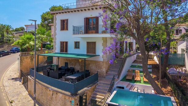 Un bâtiment à deux étages doté d’un balcon, d’un espace extérieur aménagé pour s’asseoir et d’une piscine.