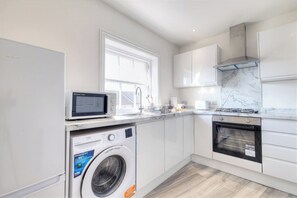 Een moderne keuken met een wasmachine, magnetron, fornuis en oven.
