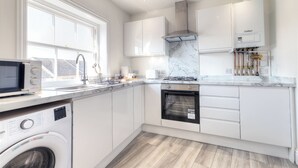 Una cocina moderna con armarios blancos, lavadora integrada, microondas y estufa.