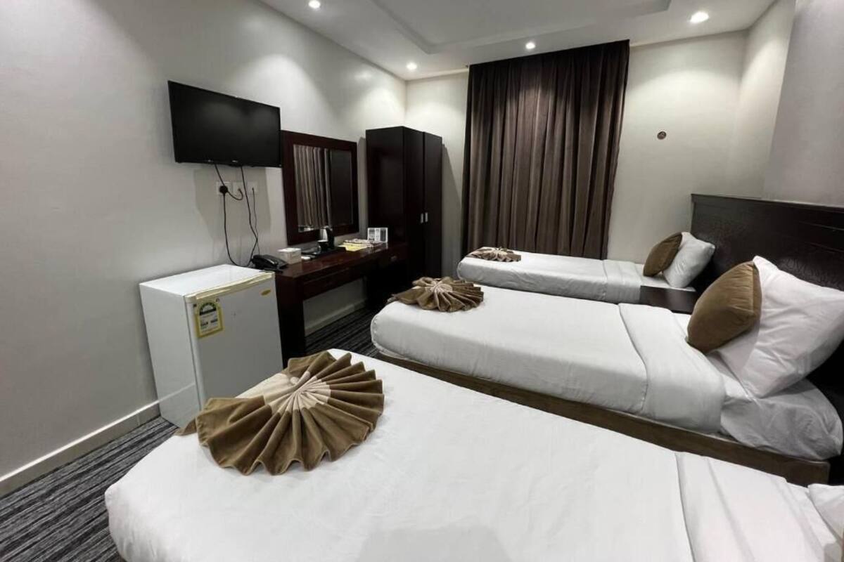 Una habitación de hotel con dos camas, televisión, escritorio y armario.