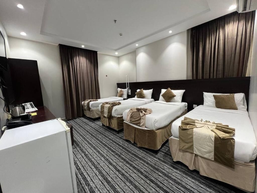 A hotel room with four beds, a desk with a telephone, and a television.