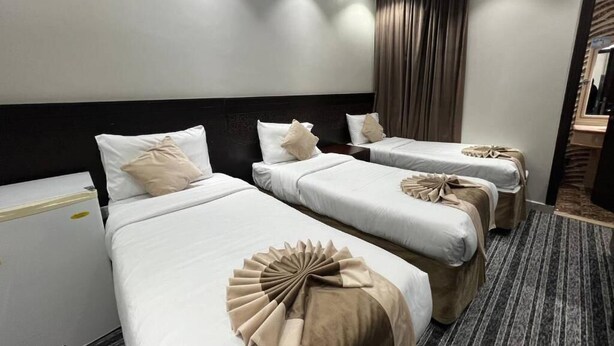 Ein Hotelzimmer mit drei Betten, einem dunklen Kopfteil und einem großen Spiegel.