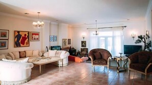 Un salón amplio con un conjunto de sofás, sillones, una mesa de centro y obras de arte en las paredes.