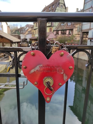 A heart-shaped padlock with a message on a metal railing.