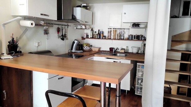 Une cuisine compacte avec une table en bois, un four encastré et divers ustensiles et appareils de cuisine.