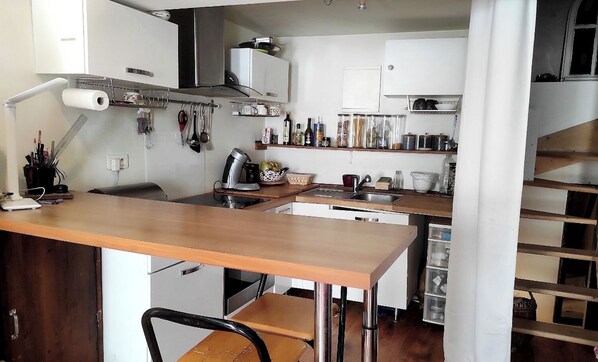 A kitchen with a wooden table, white cabinets, and a variety of kitchen utensils and appliances.