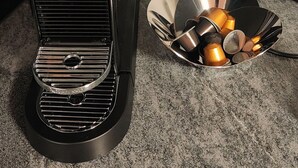 A coffee maker with a metal tray, a power outlet, and a cable on a countertop. - Casa Suvita / Alpine Luxury Apartment (Obersaxen Mundaun)