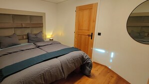 A bedroom with a bed, a wooden door, and a mirror. - Casa Suvita / Alpine Luxury Apartment (Obersaxen Mundaun)
