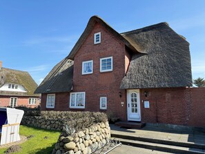 A red brick house with a thatched roof, white windows, and a stone wall. - House Inselfriede Pidder Lüng 5: 300 m to the beach in Westerland (Westerland)