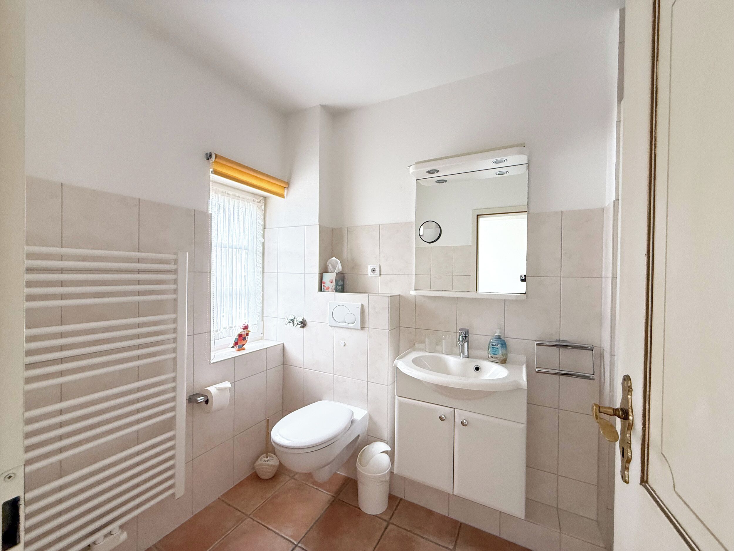 Une petite salle de bain avec des toilettes, un lavabo et une fenêtre.
