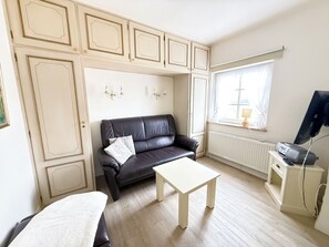 A room with a black leather sofa, a white table, and a TV on a stand. - House Inselfriede Pidder Lüng 5: 300 m to the beach in Westerland (Westerland)