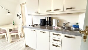 Una cucina compatta con zona pranzo, dotata di mobili, macchina da caffè, bollitore e lavello.