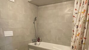 Et badeværelse med toilet, vask, bruser og en gul måtte.