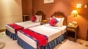A hotel room with two beds, each with a red and blue floral bedspread, wooden headboards, and a nightstand with a lamp and phone. - 1-bedroom hotel in enchanting Dhaka with fitness room and AC (Dhaka)