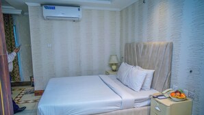 A hotel room with a bed, bedside table, lamp, air conditioning unit, and a wall with a unique pattern. - 1-bedroom hotel in enchanting Dhaka with fitness room and AC (Dhaka)