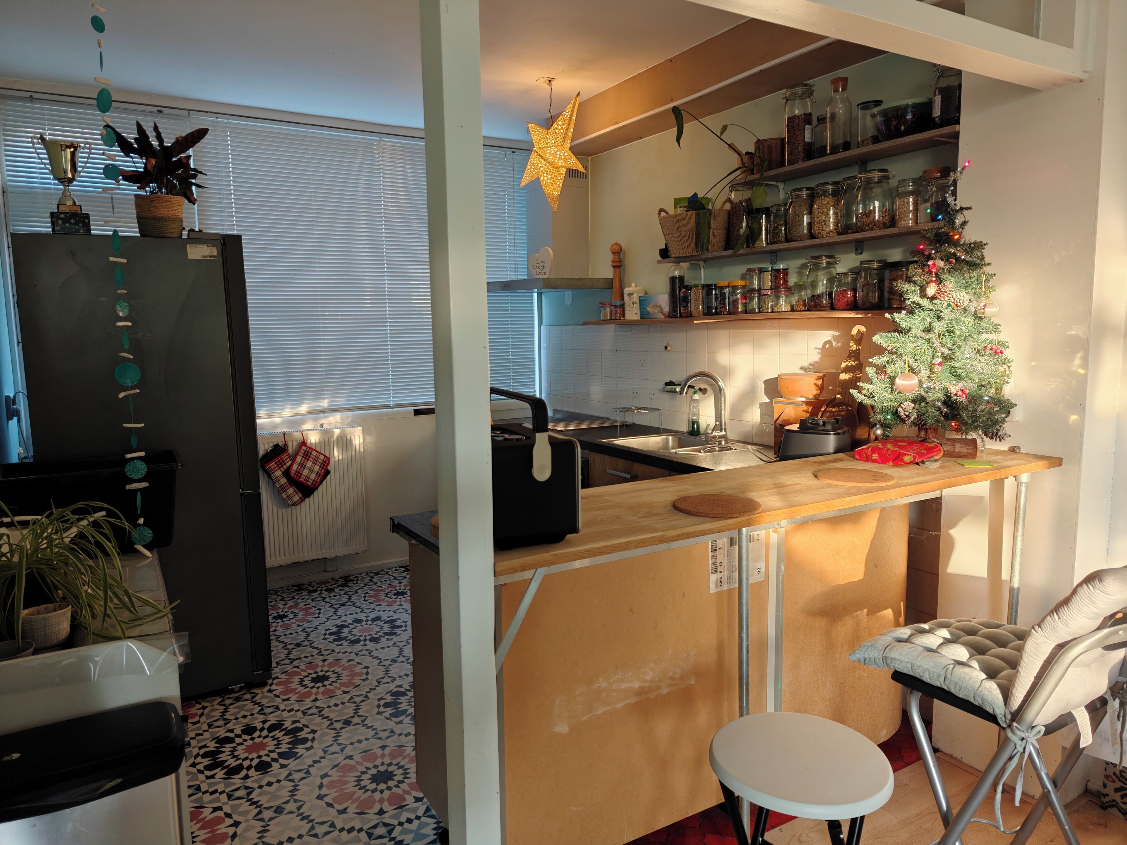 A kitchen with a refrigerator, stove, sink, and a small Christmas tree.